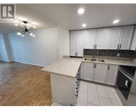 A kitchen with white cabinets and a wooden floor.