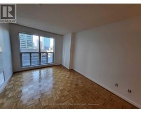 A room with wooden flooring and a large window overlooking a cityscape.