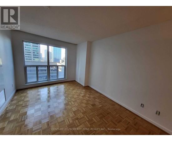 A room with wooden flooring and a large window overlooking a cityscape.