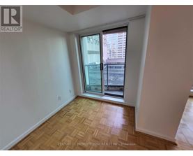 A room with a wooden floor and a window overlooking a cityscape.