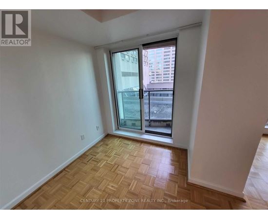 A room with a wooden floor and a window overlooking a cityscape.