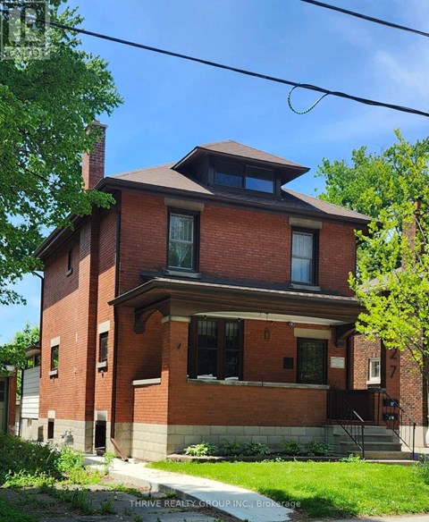 A red brick house with a small porch and a small window on the second floor.