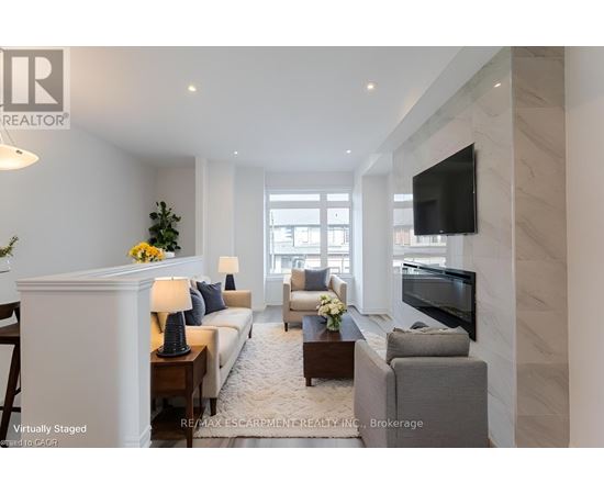 A living room with a white sofa, a grey armchair, a coffee table, and a flat-screen TV mounted on the wall.