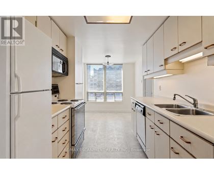 A kitchen with white cabinets and a black microwave.