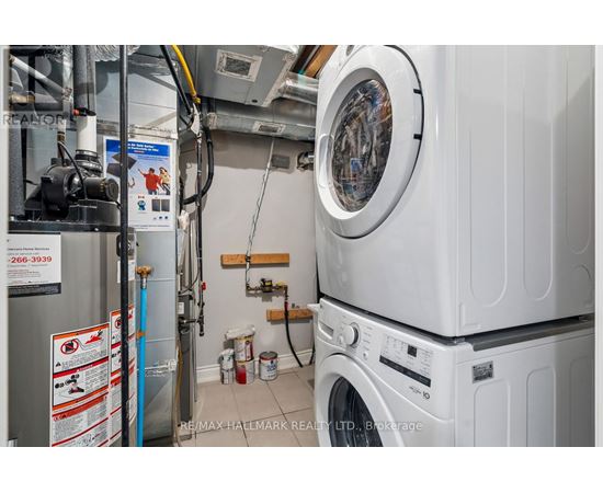 A washing machine and dryer are stacked on top of each other in a small laundry room.