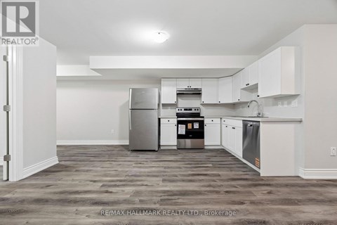 A kitchen with white cabinets and a grey floor.