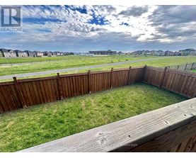 A wooden deck overlooks a grassy area with a cloudy sky in the distance.