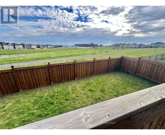 A wooden deck overlooks a grassy area with a cloudy sky in the distance.