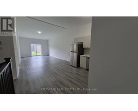 A spacious room with wooden flooring and a window overlooking a green area.