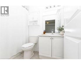 A white bathroom with a toilet, sink, and cabinet.