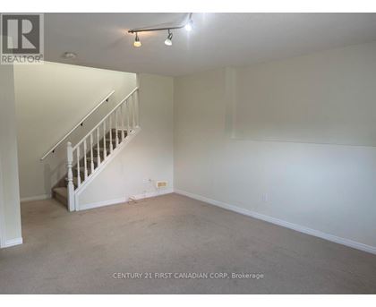 A spacious room with a staircase and carpeted floor.