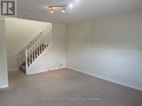 A spacious room with a staircase and carpeted floor.
