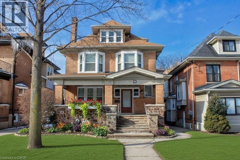 A large house with a front yard and a tree.