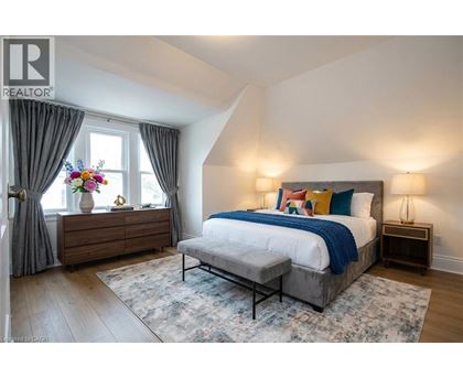 A bedroom with a large bed and a wooden dresser with a vase of flowers on top.