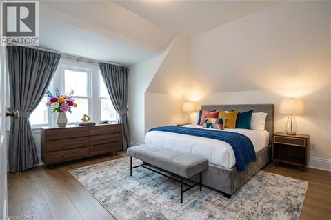A bedroom with a large bed and a wooden dresser with a vase of flowers on top.
