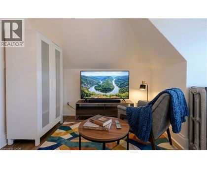 A living room with a television on a stand and a chair with a blue blanket on it.