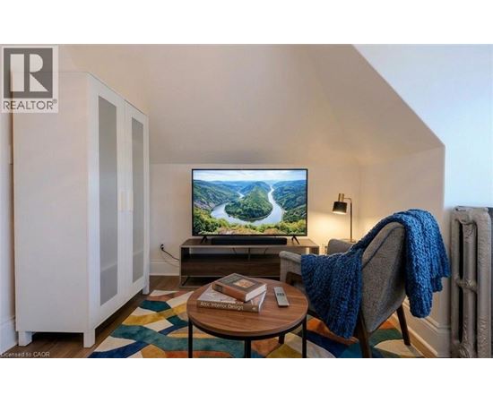 A living room with a television on a stand and a chair with a blue blanket on it.