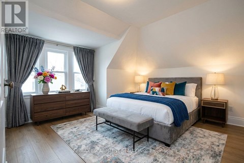 A bedroom with a large bed and a wooden dresser with a vase of flowers on top.