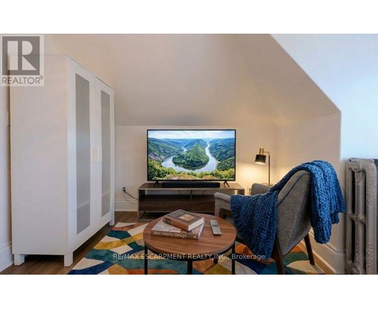 A living room with a television on a stand and a chair with a blue blanket on it.