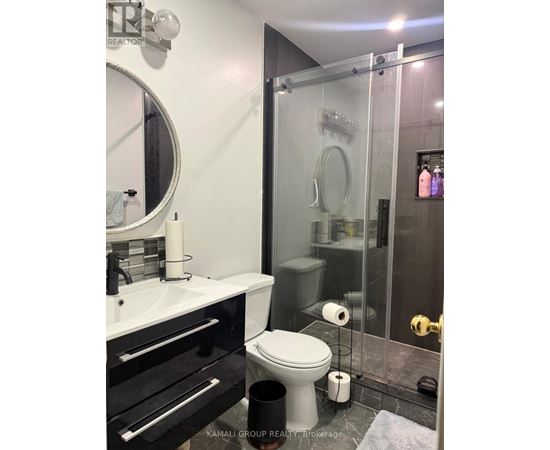 A white toilet sits in a bathroom next to a sink and a glass shower stall.