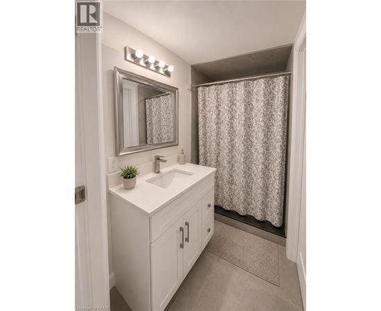A bathroom with a sink, mirror, and shower curtain.