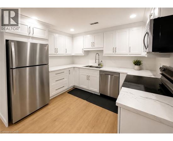 A modern kitchen with white cabinets and a stainless steel refrigerator.