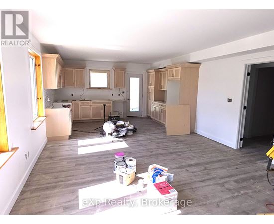 A room with wooden floors and white walls is under renovation.