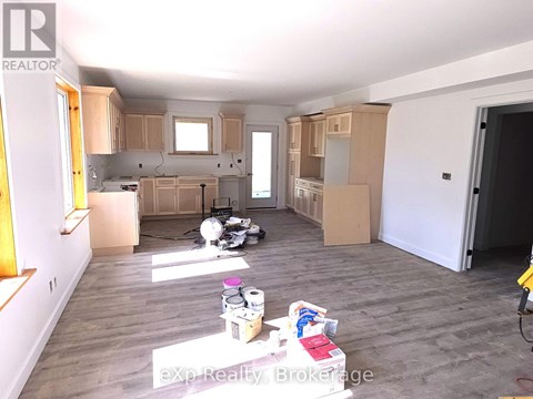 A room with wooden floors and white walls is under renovation.