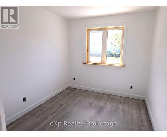 A room with a window and wooden flooring.