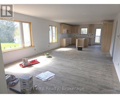 A room with wooden flooring and unfinished walls is shown.
