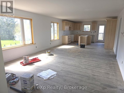A room with wooden flooring and unfinished walls is shown.