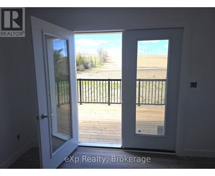 A white door with a glass window is open to a balcony with a black railing.