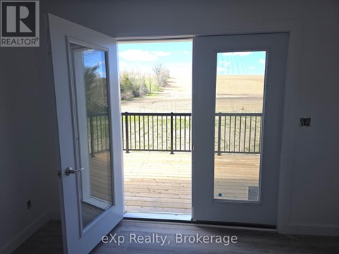 A white door with a glass window is open to a balcony with a black railing.