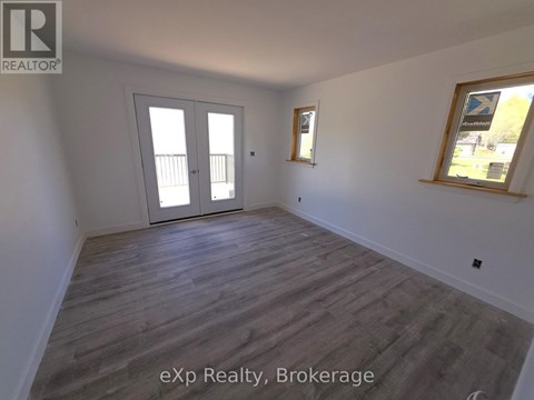 A room with a sliding door and a window with a view of a tree.