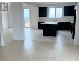 A spacious kitchen with black cabinets and a white island.
