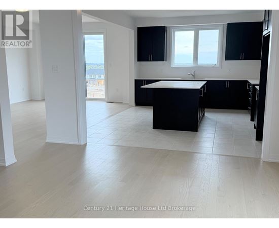 A spacious kitchen with black cabinets and a white island.