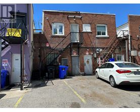 A white car is parked in a parking lot in front of a brick building.