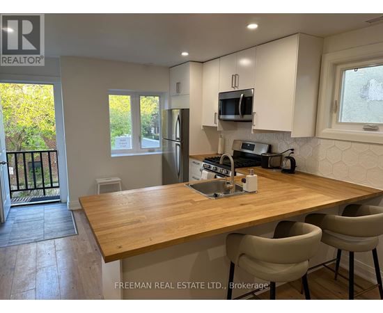 A kitchen with a wooden table and chairs, and a window with a view of trees.