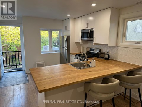 A kitchen with a wooden table and chairs, and a window with a view of trees.