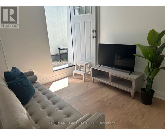 A living room with a couch, a television, and a potted plant.