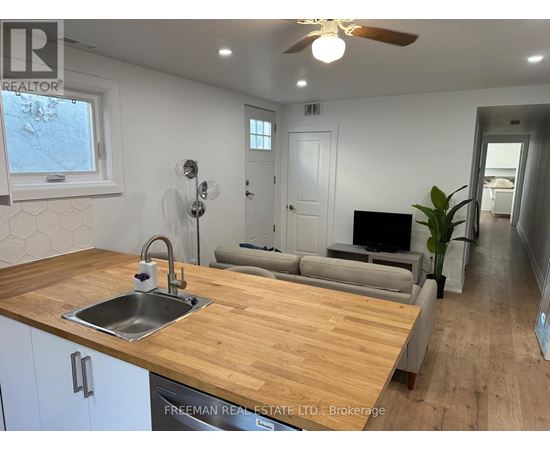 A kitchen with a wooden countertop and a stainless steel sink.