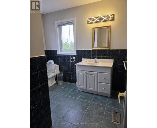 A bathroom with a toilet, sink, and mirror.
