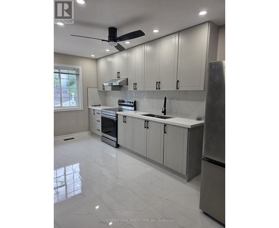 A modern kitchen with a stainless steel refrigerator and a ceiling fan.