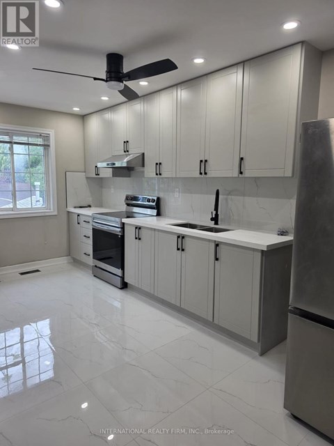 A modern kitchen with a stainless steel refrigerator and a ceiling fan.