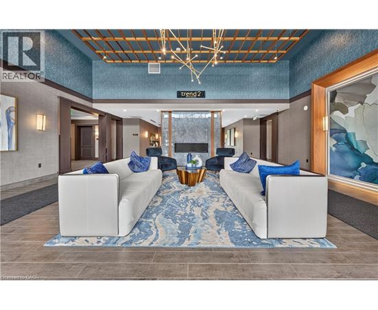 A living room with a white couch and a blue rug.