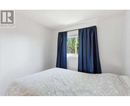 A bedroom with a bed and a window with blue curtains.