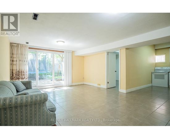 A living room with a grey couch and a sliding glass door leading to a balcony.