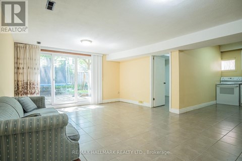 A living room with a grey couch and a sliding glass door leading to a balcony.