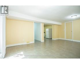 A spacious room with beige walls and tiled flooring.