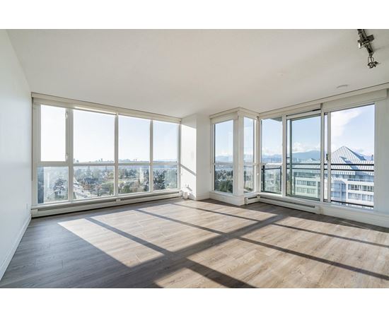 A large empty room with wooden floors and large windows.